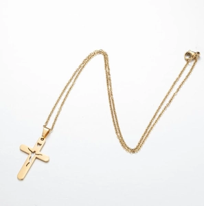 Macro shot of gold cross necklace with abstract figure cutout on polished lobster clasp chain