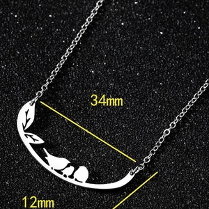 Collier argenté avec pendentif oiseau et branche de feuilles, dimensions 34mm sur noir
