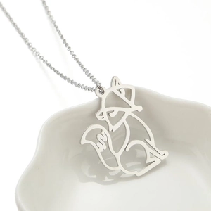 Detail view of a silver minimalist cutout fox pendant necklace on a ceramic floral tray