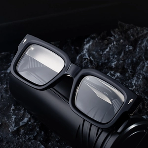 Lunettes de soleil rétro carrées avec rivets argentés sur un support en pierre noire mate