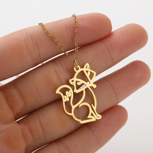 Close-up of a golden hollow fox pendant necklace held against a white background