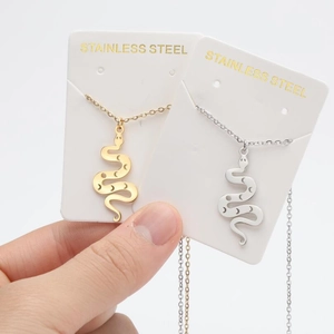 Detail showing curved snake pendants in gold and silver stainless steel on display card