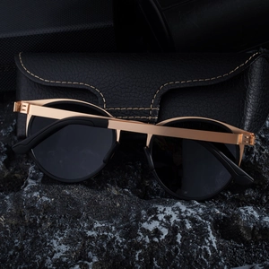 Close-up of retro polarized sunglasses with gold metal frame on black volcanic rock