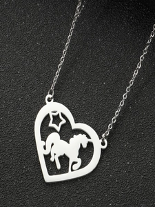 Vue détaillée d'un pendentif cœur argenté avec licorne et étoile sur fond noir texturé