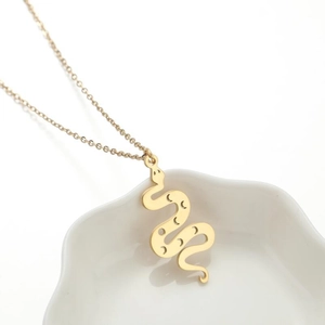 Gold stainless steel snake pendant necklace with crescent moon cutout on white tray