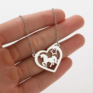 Vue détaillée du pendentif coeur ajouré avec silhouettes de licorne et d'étoile sur chaîne fine
