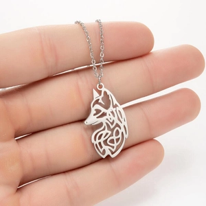 Détail du collier pendentif tête de loup argentée avec motif géométrique sur la main