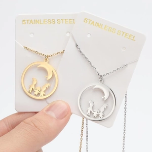 Detail of gold and silver stainless steel necklaces featuring moon and family silhouettes