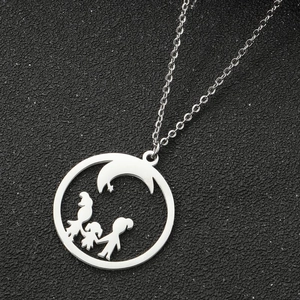 Macro shot of silver circular pendant with family silhouette and crescent moon detail