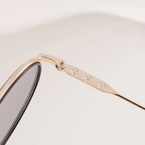 Détail des branches de lunettes de soleil en métal doré avec reliefs floraux élégants