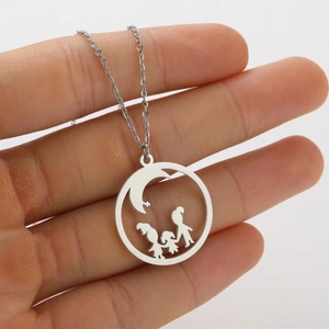 Macro view of silver round pendant with cutout silhouettes of three children holding hands