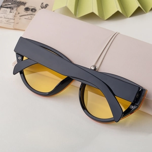 Close-up of black cat-eye sunglasses with amber lenses and a folding storage case