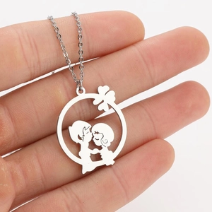 Détail d'un collier argenté avec pendentif découpé montrant un couple qui s'embrasse