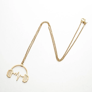 Détail du pendentif accordéon note musicale dorée avec motif d'onde de fréquence