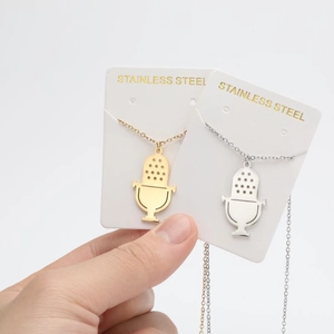 Détail des pendentifs microphone en argent et or avec des motifs de maille sur collier