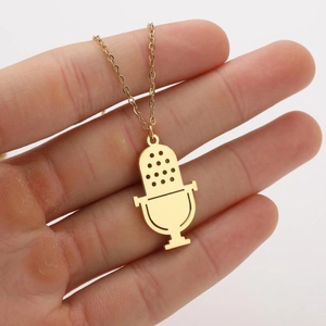 Gros plan d'un collier pendentif micro doré tenu à la main montrant les détails musicaux