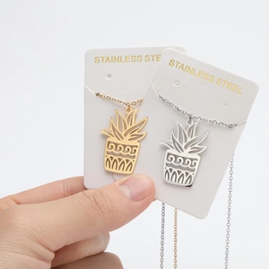 Detailed view of hollow pineapple plant pendants in gold and silver stainless steel finishes