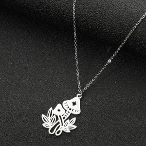 Macro shot of silver mushroom and leaf pendant with moon patterns on black texture