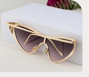 Detail of oversized cat-eye sunglasses featuring golden metal frames and purple gradient lenses