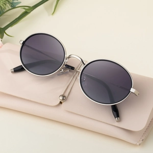 Lunettes de soleil ovales en métal argenté avec verres gris et étui sur fond beige doux