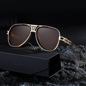 Luxus Pilotenbrille in Gold mit braunem Verlauf und Brillenetui auf schwarzem Felsen