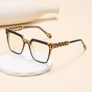 Cat eye tortoiseshell and black leopard print glasses frame on a white geometric display stand