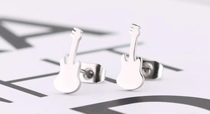 Macro detail of silver guitar stud earrings in stainless steel on white board