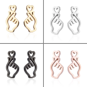 Detail view of heart gesture stud earrings in gold, silver, black, and rose gold finishes