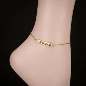 Détail du pendentif lettre Scorpio sur une fine chevillère en acier doré brillant
