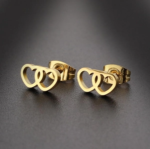 Detailed close-up of interlocking gold heart stud earrings with metallic gloss finish
