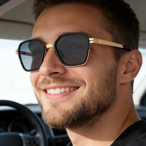 Detail of square polarized sunglasses with gold metal temples worn by a man driving