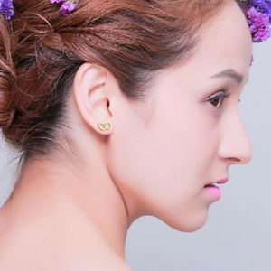 Minimalist double heart golden stainless steel stud earrings worn on female earlobe
