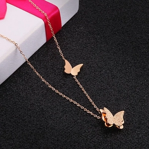 Detail of rose gold double butterfly necklace with matte finish on a white gift box