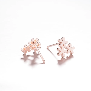 Dettaglio ravvicinato di orecchini a fiore in oro rosa con texture elegante