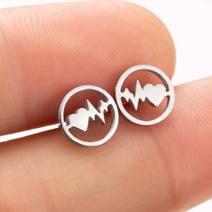 Vue macro des boucles d'oreilles circulaires argentées avec design cœur et électrocardiogramme