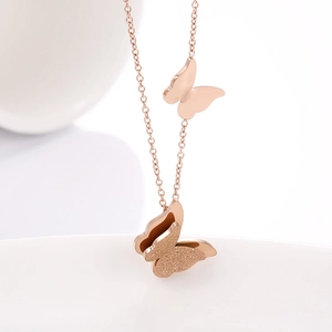 Detail of rose gold double butterfly necklace with polished and frosted metal finishes