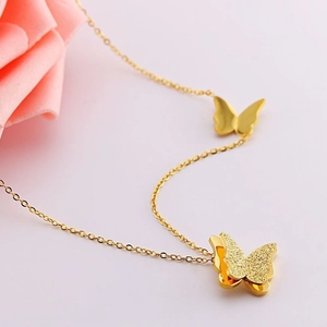 Detail of gold double butterfly necklace with textured sandblast and polished finish