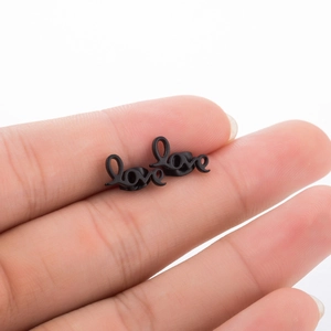 Minimalist black stainless steel love letter stud earrings held for size display