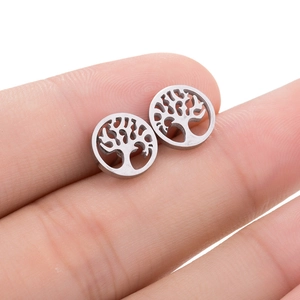 Macro view of silver tree of life earrings with intricate hollow design on finger