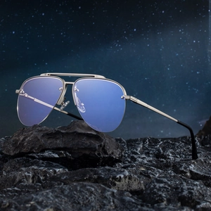 Classic silver aviator sunglasses with blue reflective lenses on a dark stone background