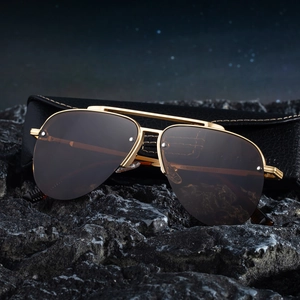 Classic aviator sunglasses with gold metal frame and brown lenses on a textured rock