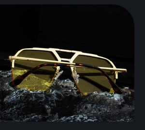 Macro detail of gold half-rim aviator sunglasses with yellow lenses on dark rock