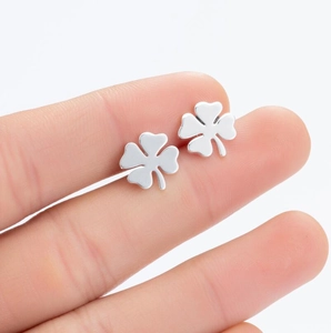 Detailed close-up of polished silver clover stud earrings held to show scale and texture