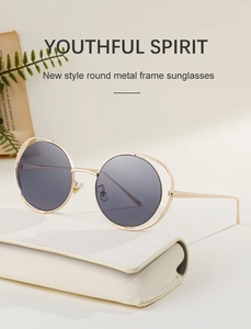 Detail of round metal sunglasses with double gold frames and cream leather case