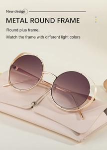 Detail of round metal sunglasses with gold frame and gradient lenses on a leather case