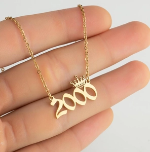 Macro view of gold-plated year 2000 crown pendant necklace on an O-shaped chain