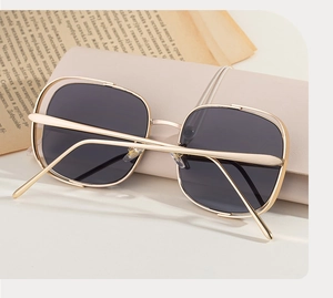 Vue détaillée de lunettes de soleil carrées sur étui beige avec branches en métal
