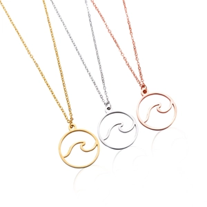 Dettaglio di tre collane con ciondolo a onda in oro, argento e oro rosa su bianco