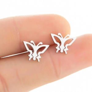 Macro detail of minimalist butterfly stud earrings in polished stainless steel on fingertip