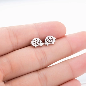 Detailed view of silver hedgehog stud earrings in hollowed stainless steel on fingertips